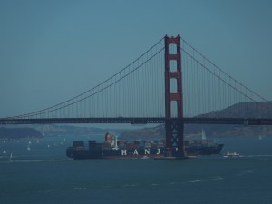 A massive container ship cruises under the Golden Gate Bridge